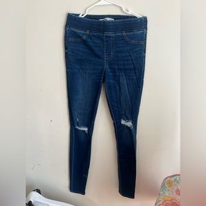 A pair of blue jeans with rips in the knees.
